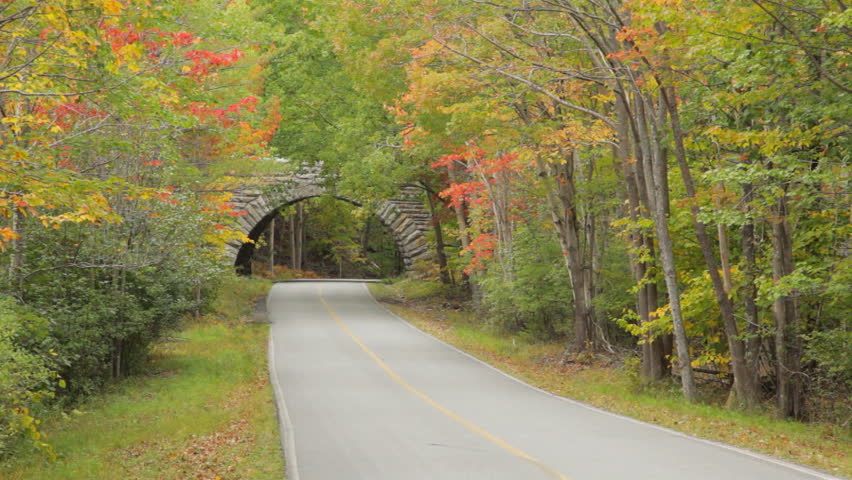 Two cars drive on a stone bridge on Park Loop Road, over Duck Brook Road, in Acadia National Park in Autumn.