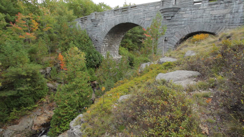 One of the carriage road stone bridges in Acadia National Park in Autumn. The clip begins on  Duck Brook Bridge, and pans to Duck Brook amidst colorful Fall foliage. 