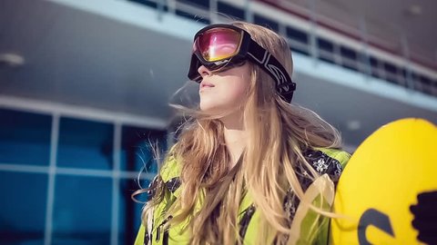 Girl with a Snowboard is Taking off her Sunglasses