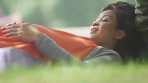 4K Happy pregnant couple relaxing in the park, feeling baby kicking. Shot on RED Epic.