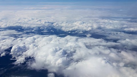Traveling by air above clouds. View through an airplane window. Flying over the Mediterranean Sea through cirrus and cumulus clouds and little turbulence, showing Earth's atmosphere.