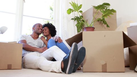 Smiling couple unpacking cardboard boxes in their new home