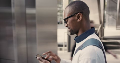 African American Man using business app on smart phone walking in city. Handsome young businessman communicating on smartphone smiling confident. Urban black male professional commuting in his 20s