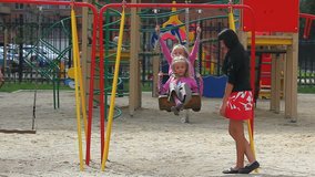 Mother looking after her daughters on swing