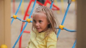 Little girl sitting in playground net 