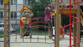 Two little girls climbing on playground net 