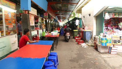JAKARTA, INDONESIA - MARCH 09, 2015: POV walk through street restaurants lane, traditional fastfood area. Small eatery kiosks placed one by one along passageway, few table and seats in front of each