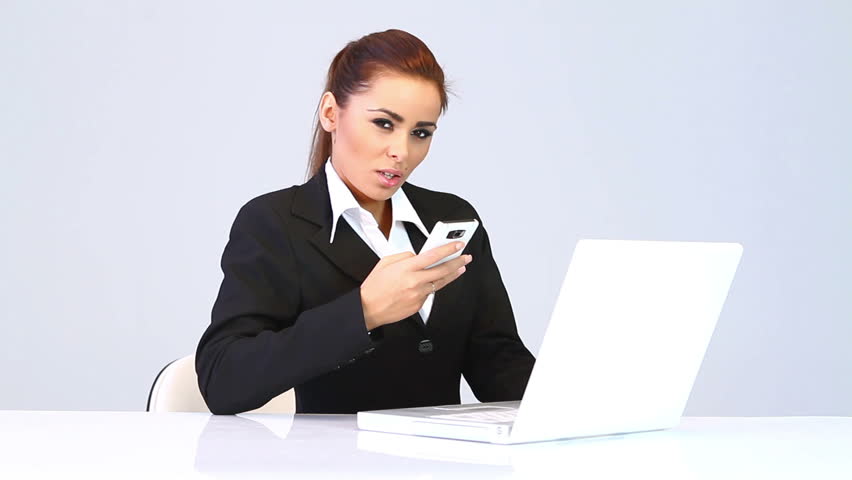 Business woman sitting at the desk and talking mobile phone