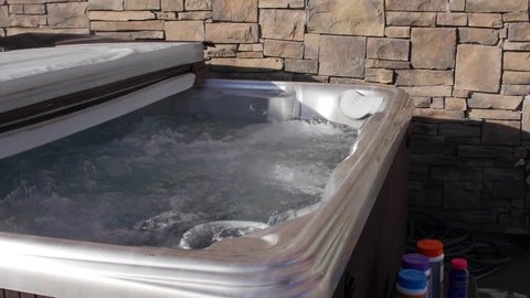 A man prepares to do weekly maintenance on his hot tub and put chemicals in it to clean it.