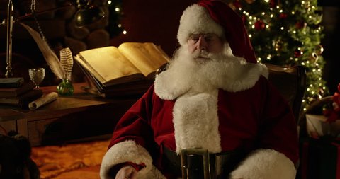 Santa Claus uses his smart phone after putting his glasses on - facing camera 