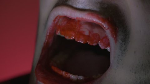 Closeup on the mouth of a zombie with a strobe light and red background. Great Halloween clip to add in you horror, scary, spooky projects.