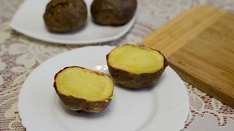 Woman adds butter in a baked potatoes