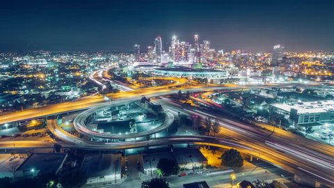 Aerial view of traffic on freeway interchange in downtown Los Angeles skyline at night. 4K UHD timelapse 