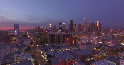 Beautiful aerial view of colorful illuminated city of downtown Los Angeles skyline at sunset twilight dusk night. 4K UHD.