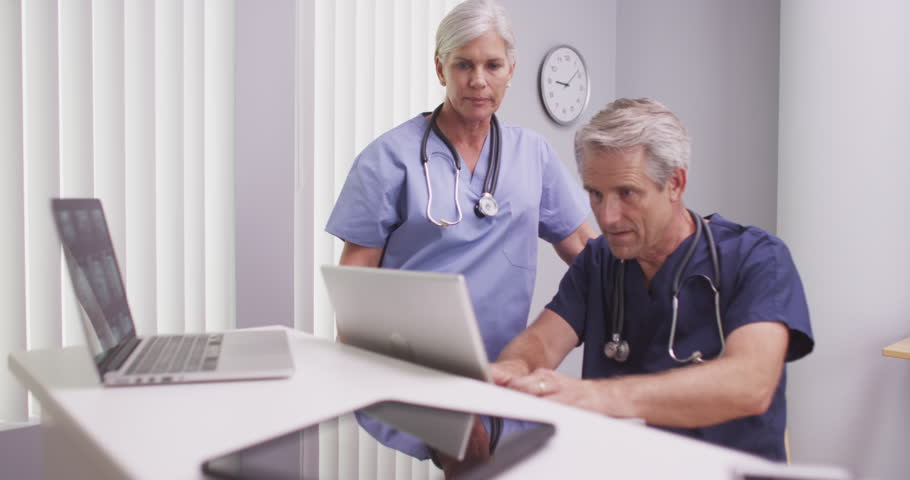 Two caucasian mature medical practitioners wearing scrubs | Shutterstock HD Video #13244036