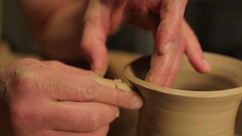 Potter special tools handles clay. Master crock. The creative process in the studio. Twisted potter's wheel. Man creates a work of art. The ability to create beauty. Master kneads the clay. Pottery.