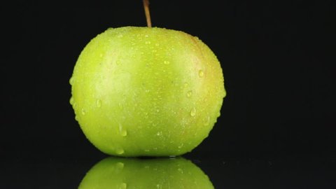 Green apple  in drops of dew rotates on its axis. HD
