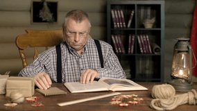 Smart senior man reading encyclopedia and making notes  - Powered by Shutterstock - Get 15% off with code: PIKWIZARD15
