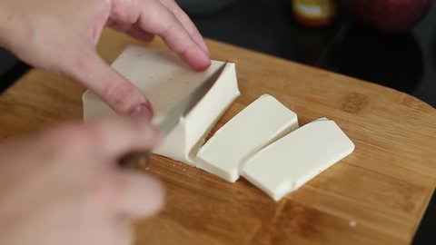Cutting tofu with knife on a cutting board