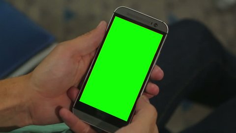 Closeup of male hands holding smart phone with green screen prekeyed for effects. Useful mobile application booking, ordering services, shopping online. Modern communication technology, gadget games
