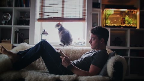 Cinemagraph (Photo-Motion) of a Young Relax Adult Reading a Book on the Couch Adlı Stok Video