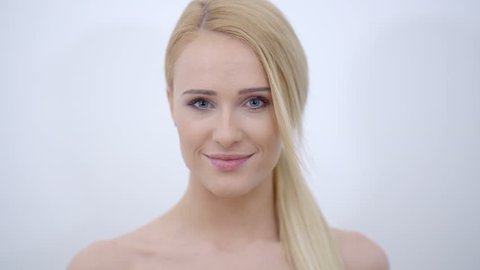 Close up Smiling Bare Woman with Blond Hair Touching her Face While Looking at the Camera. Isolated on Gray Background.