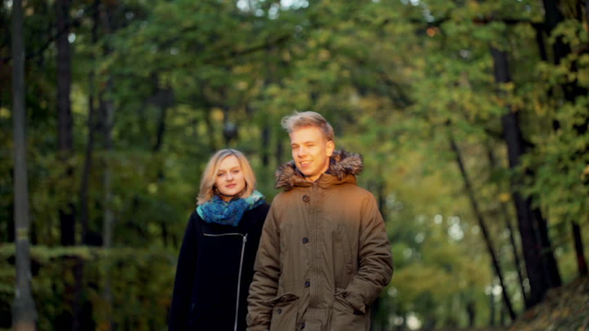 Lovely couple walking in the park and smiling to the camera
