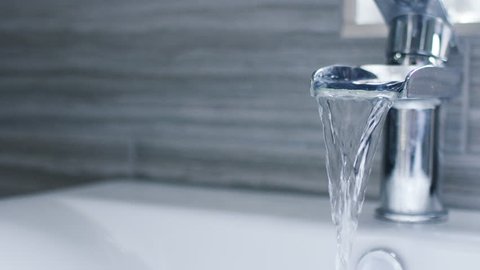 4K Running water from a waterfall tap in a bathroom, in slow motion