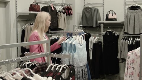 The consultant helps to choose a dress to the girl