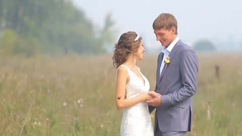 Beautiful wedding couple is walking on the green field smoked