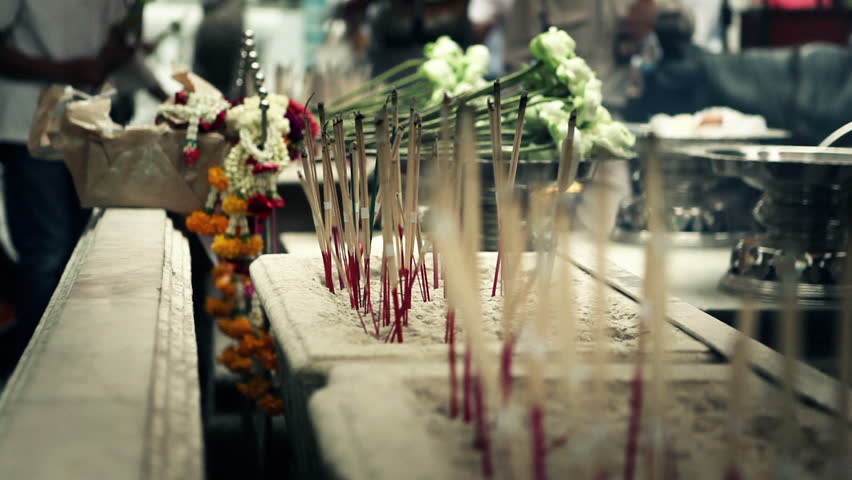 Close up of flowers and lit incense sticks in Grand Palace temple in Bangkok