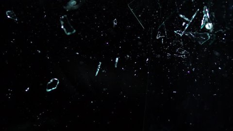 Glass shards on black, fragments breaking over the camera isolated on black breaking in slow motion in 4k 