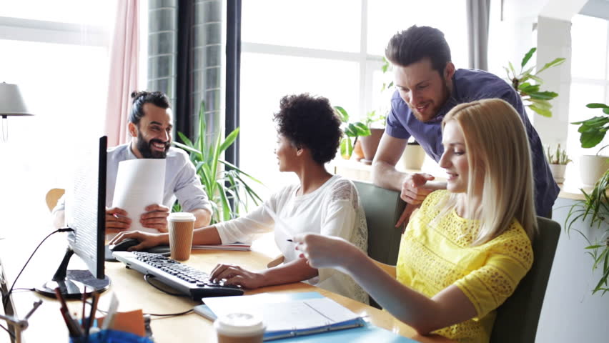 Business, startup and people concept - happy creative team with computers and folder discussing project in office | Shutterstock HD Video #13329194