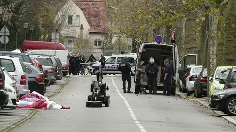 STRASBOURG, FRANCE - NOV 19, 2015: A modern EOD (Explosive Ordnance Disposal) operator dressed in a bomb suit with a bomb-disposal robot. He is neutralizing an IED (improvised explosive devices).