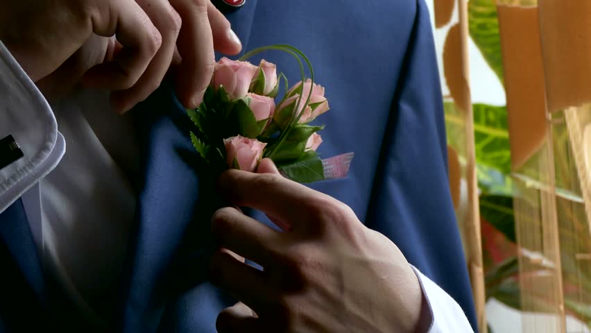 groom  boutonniere on man corrects his pocket hand