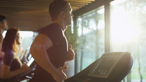 Young athletic men and women exercising and running on treadmill in sport gym. Shot on RED Cinema Camera in 4K (UHD).