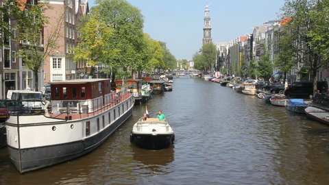 AMSTERDAM, HOLLAND - AUGUST 1: Boats sail in Amsterdam canal under the Westerchurch tower on August 1, 2011 in Amsterdam, Holland. The 17th-century canal ring area is on the UNESCO World Heritage List.