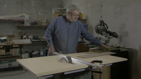 Carpenter cutting board on circular table saw in workshop, hands close up. Joiner making wooden box from parts. Man, male, woodworker, handcraft, blade, craft, holding hands, raw video, no grading.