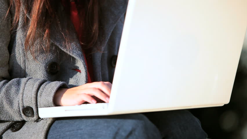 Young female student in close-up working on her laptop computer outdoors