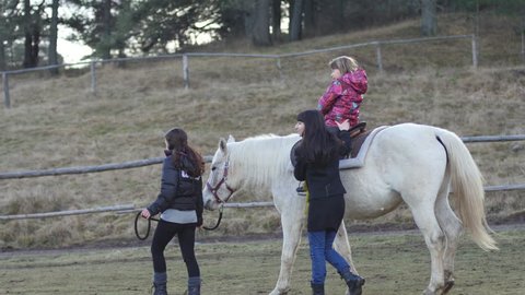 Plana, Bulgaria - DEC 08, 2015 - Nature center for horse close contact with children - therapy and rehabilitation horseriding center - kids do exersices sitting and riding in a saddle on horseback