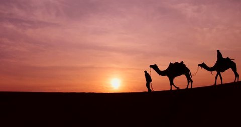 Silhouette of the Camel Trader crossing the sand dune during sunrise  at Thar Deset in Jaisalmer, India. Image is soft and contain noise due to high ISO used.
