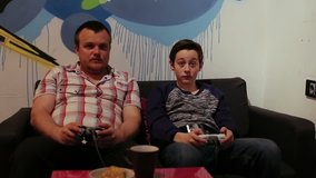 Teenager and boy on Sofa Playing in Computer Game with Joystick