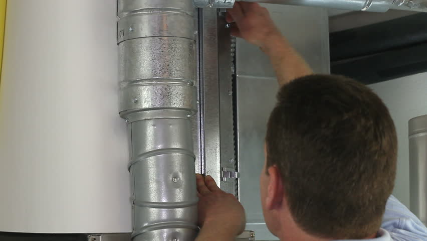 Man changing an old dirty air filter for a brand new clean one in a home furnace.