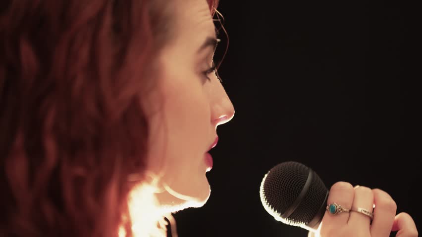 Young Woman Popstar Singing into Microphone on Stage