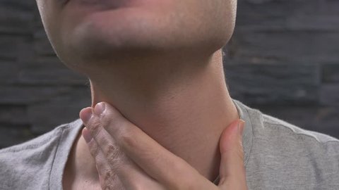 Man showing throat pain by holding his neck.