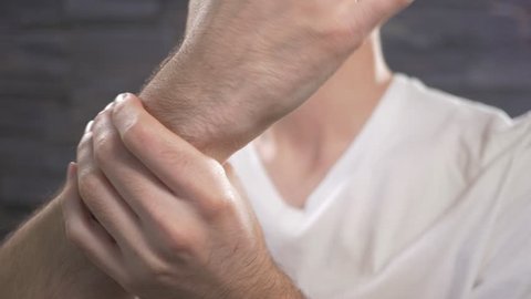 Young adult male holding his wrist to show pain.