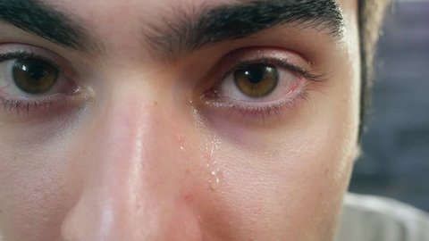 Young adult male tears rolling down his eyes. Closeup shot.