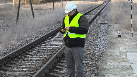 Worker with tablet PC on the snowy railwa