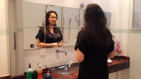 Brazilian woman fixing her hair in the bathroom.