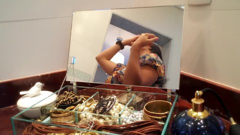 Young brazilian woman fixing her hair , reflected in a small mirror in the jewelry box.
